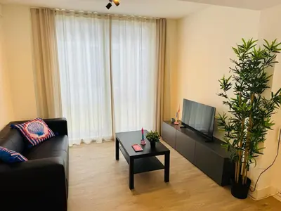 a living room with a couch and a tv and a table at Zomerhuis - Gratis parkeren! in Noordwijk aan Zee