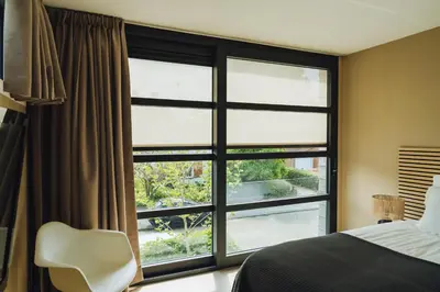 a bedroom with a large window and a white chair at Sfeervol luxe appartement Haarlemmerhout bij Haarlem Centrum en Amsterdam - gratis parkeren in Haarlem