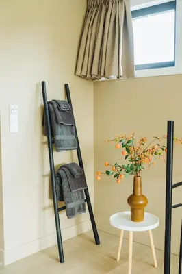a black towel rack next to a table with a vase at Sfeervol luxe appartement Haarlemmerhout bij Haarlem Centrum en Amsterdam - gratis parkeren in Haarlem