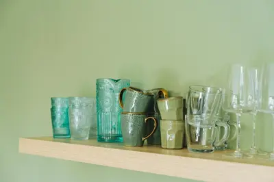a shelf filled with different colored glass vases and glasses at Sfeervol luxe appartement Haarlemmerhout bij Haarlem Centrum en Amsterdam - gratis parkeren in Haarlem