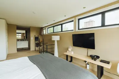 a bedroom with a large bed and a flat screen tv at Sfeervol luxe appartement Haarlemmerhout bij Haarlem Centrum en Amsterdam - gratis parkeren in Haarlem