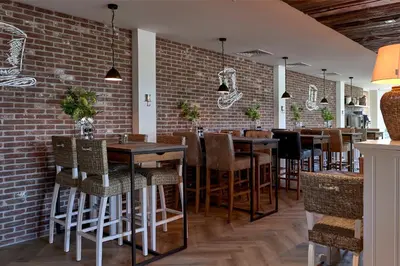 a restaurant with tables and chairs against a brick wall at Hotel Heer Hugo in Heerhugowaard