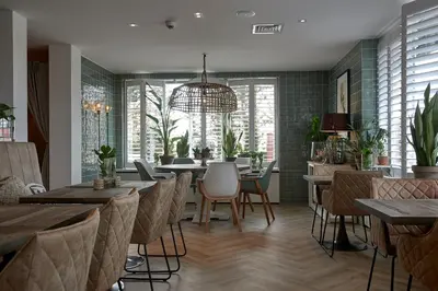 a restaurant with tables and chairs and a chandelier at Hotel Heer Hugo in Heerhugowaard