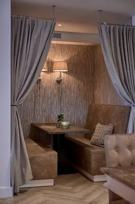 a living room with a couch and a table and curtains at Hotel Heer Hugo in Heerhugowaard