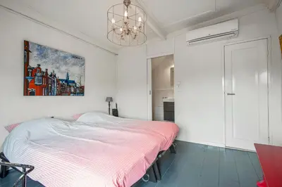 a white bedroom with a bed and a chandelier at Turfhuys aan het Spaarne in Haarlem