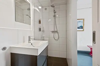 a white bathroom with a sink and a shower at Turfhuys aan het Spaarne in Haarlem