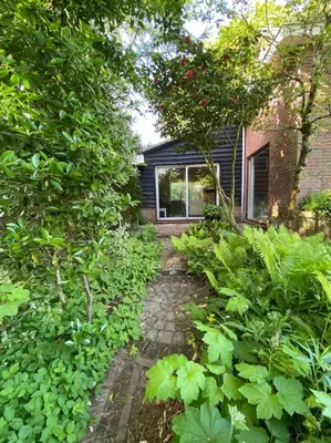 a garden with a house and trees and plants at Villa bij bos en centrum in Bergen