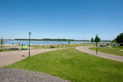 a park with people on the beach and the water at Studio Vúr de Diek in Spakenburg