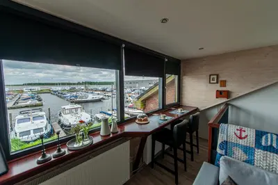 a bar with a view of a marina with boats at Studio Vúr de Diek in Spakenburg