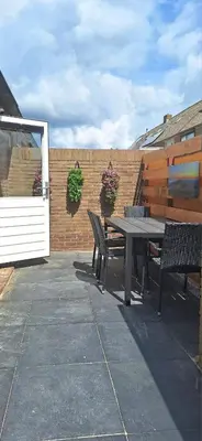 a patio with a table and benches next to a brick wall at Miles in Egmond aan Zee