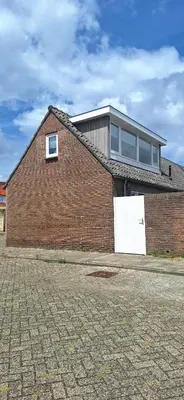 a brick building with a white door and a window at Miles in Egmond aan Zee