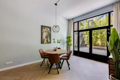 a dining room with a table and chairs and a large window at Stylish apartment next to the Amstel river- Unit D in Amsterdam