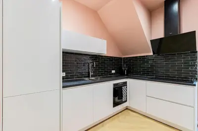 a kitchen with white cabinets and a black tile wall at Stylish apartment next to the Amstel river- Unit F in Amsterdam