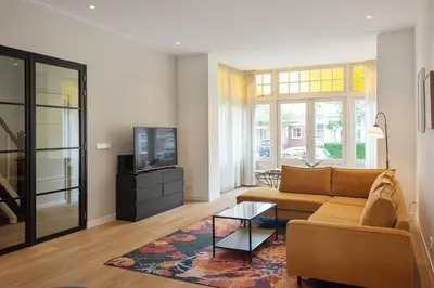 a living room with a couch and a tv at Villa Harry with private parking in Zandvoort