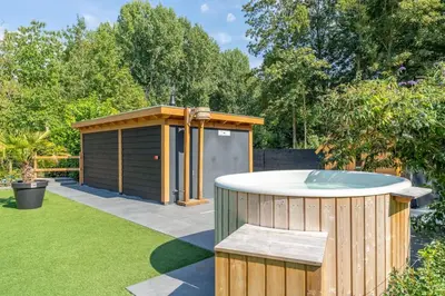 a hot tub in a garden with a shed at Yellow Tiny House with shared pool in Zeewolde