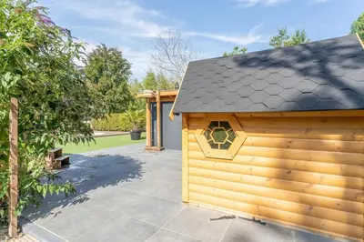 a wooden shed with a roof on a patio at Yellow Tiny House with shared pool in Zeewolde