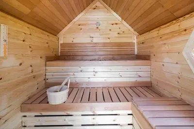 a wooden sauna with a bucket in it at Yellow Tiny House with shared pool in Zeewolde