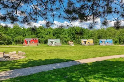 a group of colorful houses in a grass field at Blue Tiny House with HotTub in Zeewolde