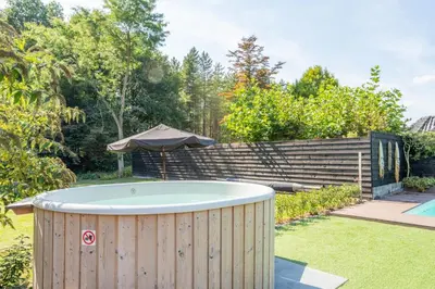 a hot tub in a garden with an umbrella at Blue Tiny House with HotTub in Zeewolde