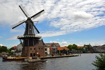 a windmill in the middle of a river with a boat at Bed & Breakfast Hotel Malts in Haarlem