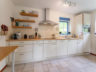 a kitchen with white cabinets and a sink at Schoorlse Duinvoet in Schoorl