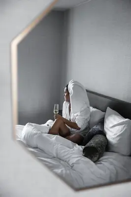 a woman sitting on a bed with a glass of wine at Hotel Twenty-Three Amsterdam Airport in Hoofddorp