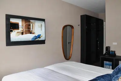 a bedroom with a mirror and a bed and a tv at Hotel Twenty-Three Amsterdam Airport in Hoofddorp