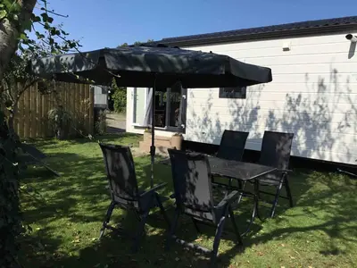 a table and chairs under an umbrella in a yard at Chalet Buitenhof 45A in Oegstgeest