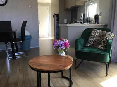 a living room with a green chair and a table at Chalet Buitenhof 45A in Oegstgeest