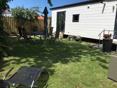 a backyard with a table and chairs and an umbrella at Chalet Buitenhof 45A in Oegstgeest