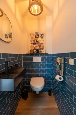 a blue tiled bathroom with a toilet and a sink at Beautifully located dune villa near Noordwijk beach in Noordwijk