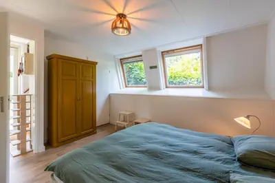 a bedroom with a bed and a ceiling fan at Beautifully located dune villa near Noordwijk beach in Noordwijk