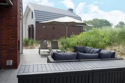a couch and an umbrella on a patio at Zonnestralen in Egmond aan den Hoef