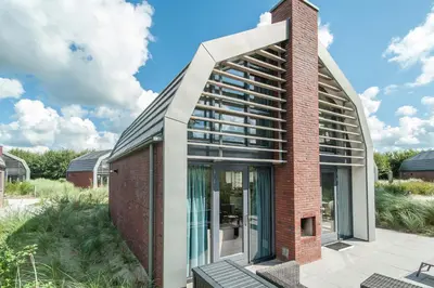 a brick building with large glass doors and a red brick at Zonnestralen in Egmond aan den Hoef