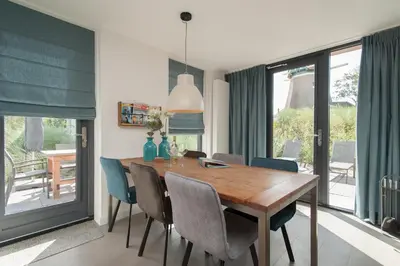 a dining room with a wooden table and chairs at Zonnestralen in Egmond aan den Hoef