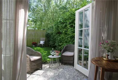 a patio with wicker chairs and a table in a yard at Casa Fiore in Bergen