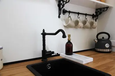 a kitchen sink with a black faucet and coffee cups at Casa Fiore in Bergen