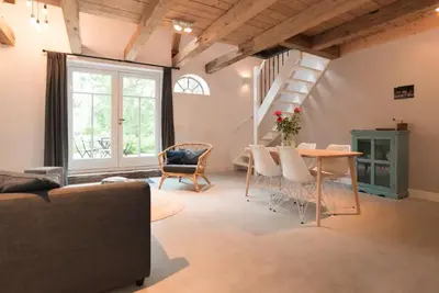 a living room with a table and chairs and a staircase at Beautiful House in The Middle of Nature in Abcoude