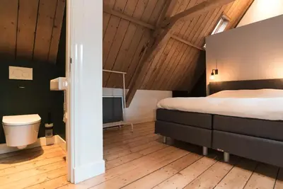 a bedroom with a bed and a toilet in a room at Beautiful House in The Middle of Nature in Abcoude
