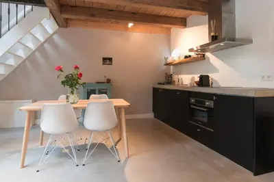 a kitchen with a wooden table and white chairs at Beautiful House in The Middle of Nature in Abcoude