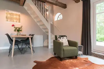 a living room with a table and chairs and a staircase at Beautiful House in The Middle of Nature in Abcoude