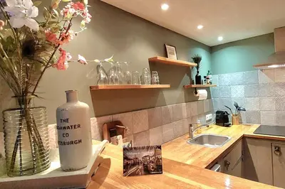 a kitchen with a sink and a vase with flowers on a counter at Have a nice stay! - Trendy Vakantiehuis Carpe Diem met eigen tuin in Noordwijk