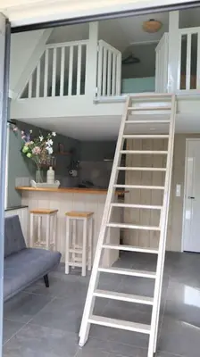 a white staircase in a living room with a couch at Have a nice stay! - Trendy Vakantiehuis Carpe Diem met eigen tuin in Noordwijk