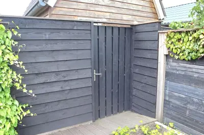 a black privacy fence with a black door at Have a nice stay! - Trendy Vakantiehuis Carpe Diem met eigen tuin in Noordwijk