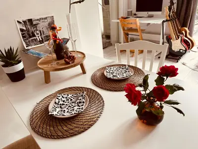 a table with two plates and a vase with red flowers at Perfectly located charming apartment MAGDALENA HOUSE for true connoisseurs in Haarlem