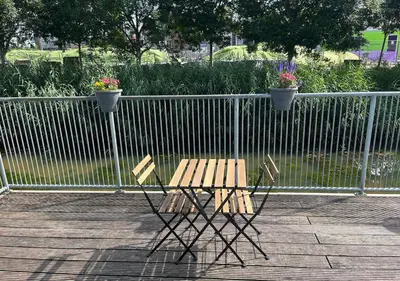 a wooden table and two chairs next to a fence at In Almere, Close to Amsterdam in Almere