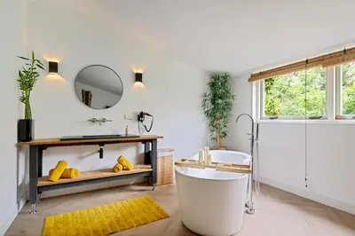 a bathroom with a tub and a sink and a mirror at Bamboe Suite Bentveld met ligbad en gratis parkeren in Bentveld