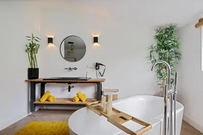a bathroom with a white tub and a mirror at Bamboe Suite Bentveld met ligbad en gratis parkeren in Bentveld