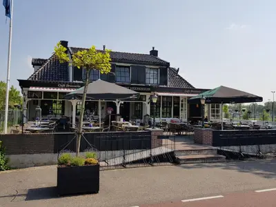 a restaurant with tables and umbrellas in front of a building at Café Brasserie Het Heerenhuis in Het Kalf