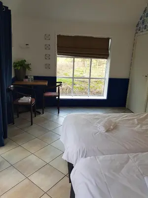 a bedroom with a bed and a desk and a window at Café Brasserie Het Heerenhuis in Het Kalf
